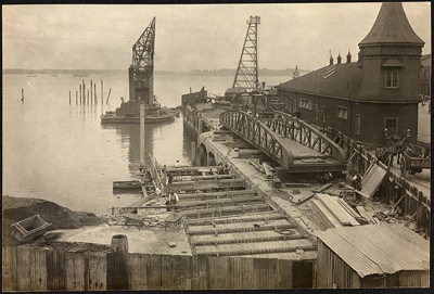 Photograph: Floating crane lifting vehicular landing bridge from old site at Queens Wharf to Northcote, 1913.; Auckland Harbour Board. Engineer's Dept.; 2010.132.232