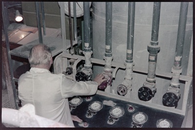 Negative - Man working at bank of vertical pipes with dials corresponding to each; 1960s; 2008.1.3084