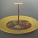 Cake plate and handle - dancers; Crown Lynn Potteries Limited; 1950-1970; 2008.1.560.1-2