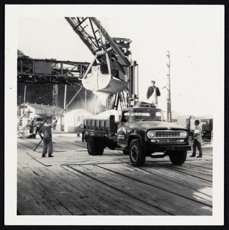 Watersiders loading bulk cargo onto Ryan Brothers truck, by crane. Gladstone Pie... eHive