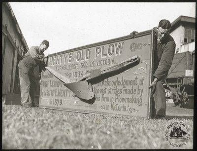 Two men holding the commemorative plaque for Henty's plough.; GS-EV-41