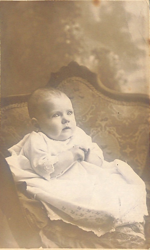 Black and white studio portrait of a baby in a white dress; ca. 1912 ...