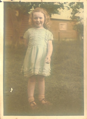 Coloured photograph of a young girl, Barbara Rees, in front of a house ...