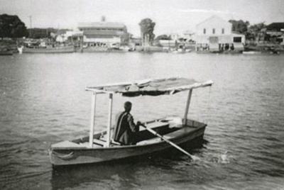 Vic Feather rowing the Penny Ferry across Ross Creek ; TMML1071 | eHive