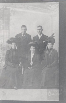 Two men standing and three women with hats sitting in photo studio; ULMPH 2000 0601 