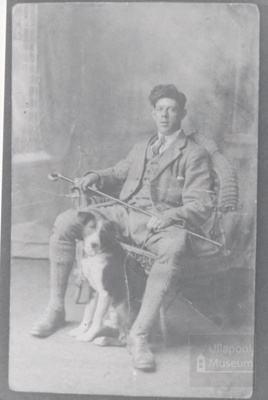 Studio photo of young man wearing tweeds sitting on Wicker chair with collie dog; ULMPH 2000 0602 