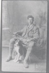 Studio photo of young man wearing tweeds sitting on Wicker chair with collie dog; ULMPH 2000 0602 