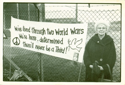 The Common Cause (8) postcard featuring a photograph of a woman standing beside an anti-war bannerers Ltd; Leeds Postcards; 1983; 2014.49.3